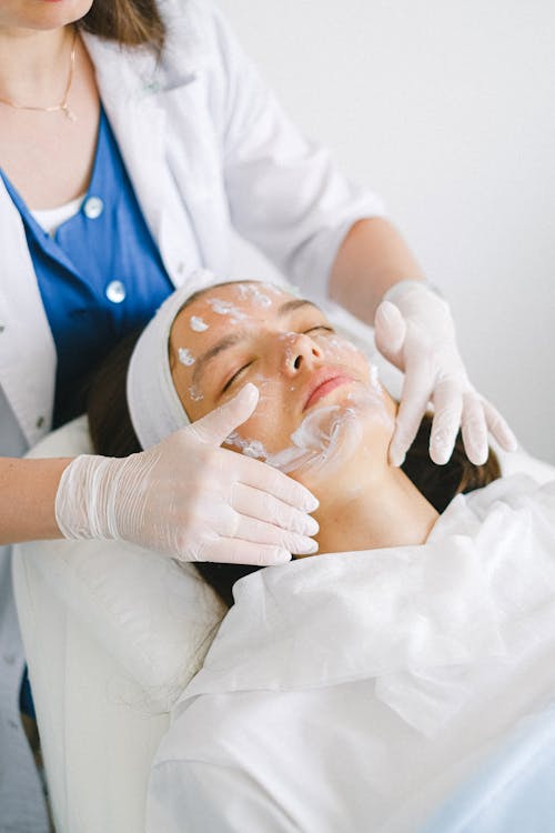 Esteticista aplicando máscara facial em cliente