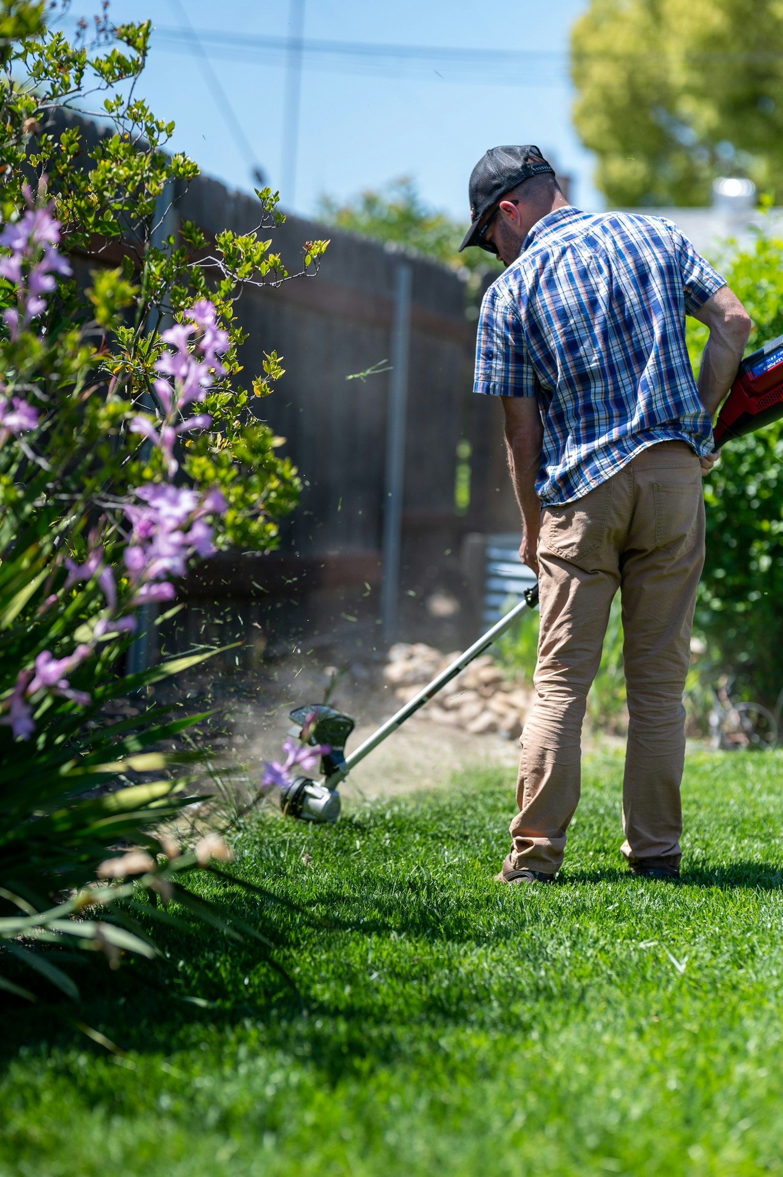 Jardineiro cortando grama em jardim residencial